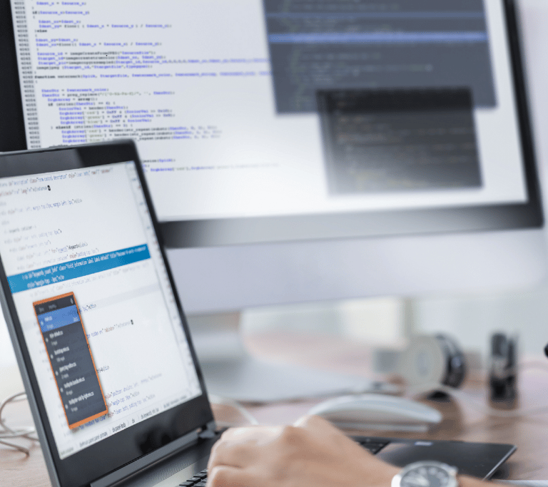 close up shot of a laptop screen and a desktop with code on it